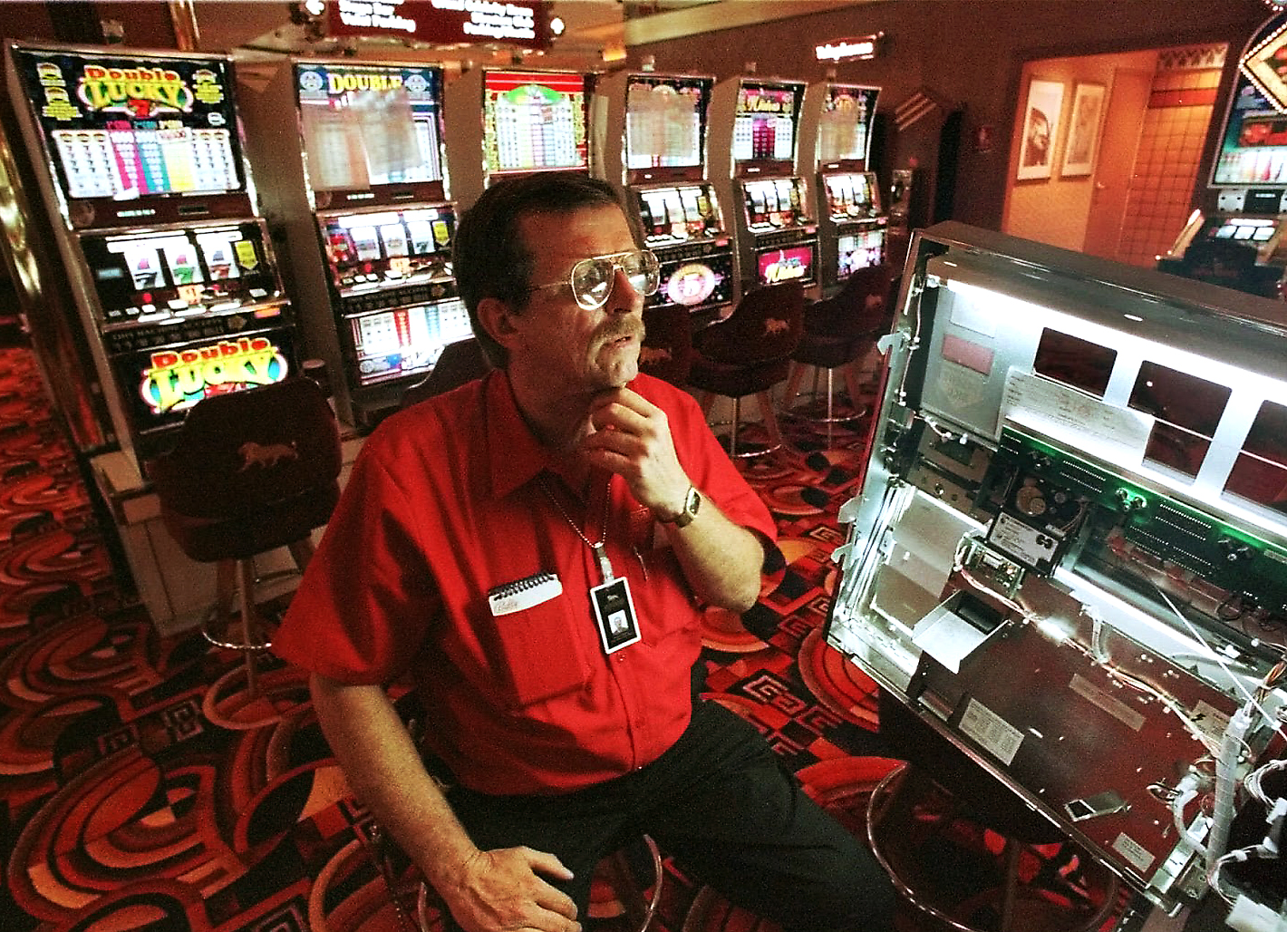 Техник внимательно осматривает устройство игрового автомата